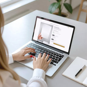 Junge Frau bestellt ihre Hochzeitseinladungen aus Büttenpapier am Laptop.